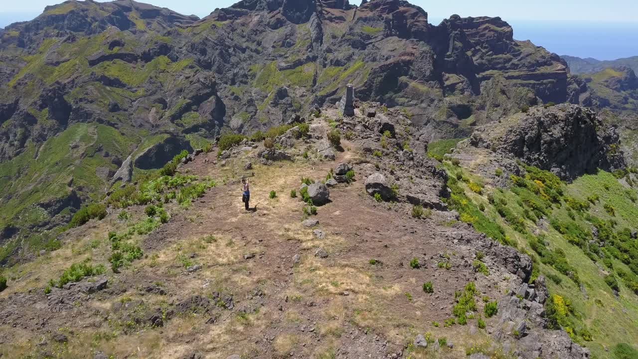 madeira, portugal - homem treinando artes marciais com uma vara no pico da montanha rochosa em um clima ensolarado - tiro aéreo drone
