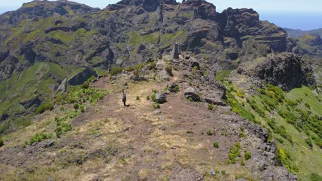 madeira, portugal - man training martial arts with a stick at the rocky mountain peak on a sunny weather - aerial drone shot