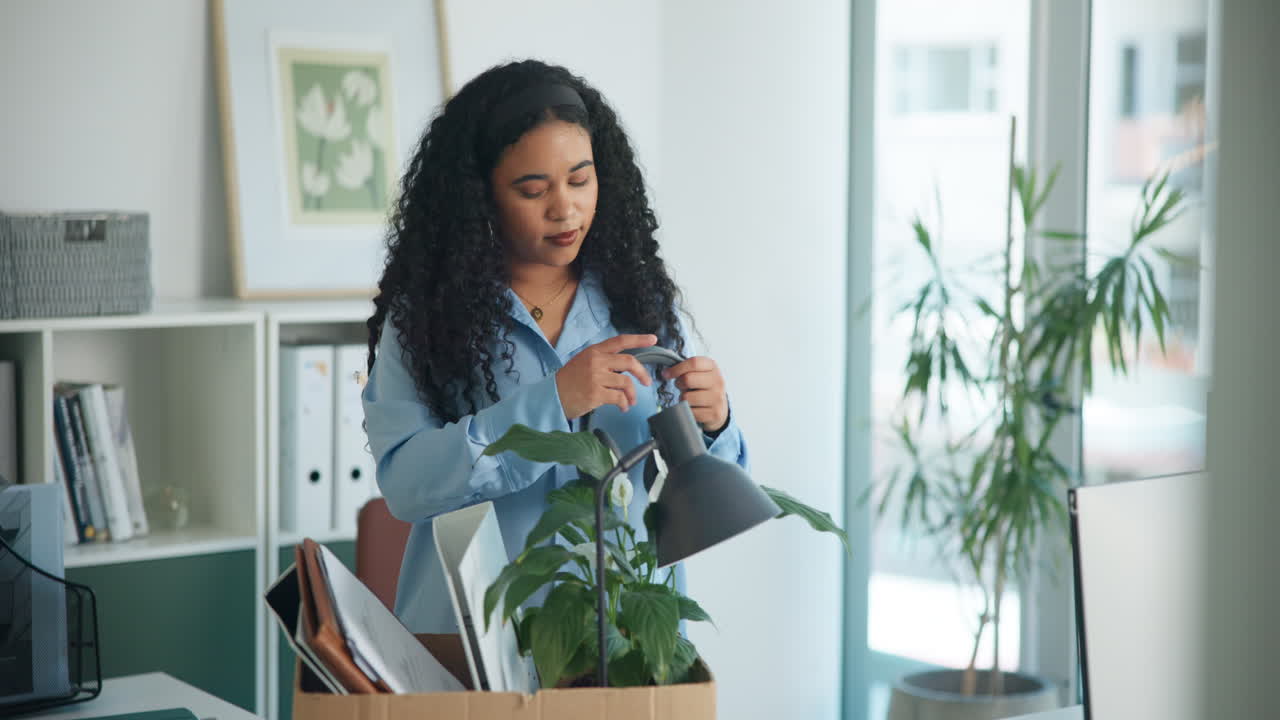 Young Woman Packing Personal Items into a Cardboard Box in an Office