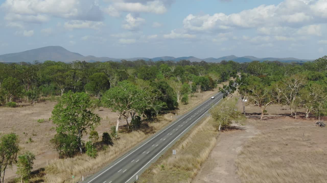 Auto isolata che percorre una strada deserta in un paesaggio rurale a St Lawrence, Clairview in Australia
