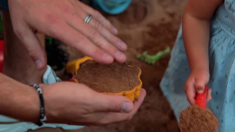 a-father-and-his-child-make-sand-shapes-on-the-playground-in-the-yard