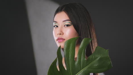 woman with creative makeup and tropical leaf