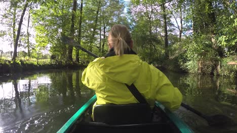 sports girl with paddle and yellow coat in kayak surrounded by beautiful nature