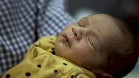 niño recién nacido durmiendo pacíficamente en un traje amarillo con puntos de polca, primer plano