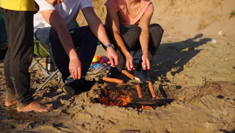 family camping trip - cooking sausages by the campfire