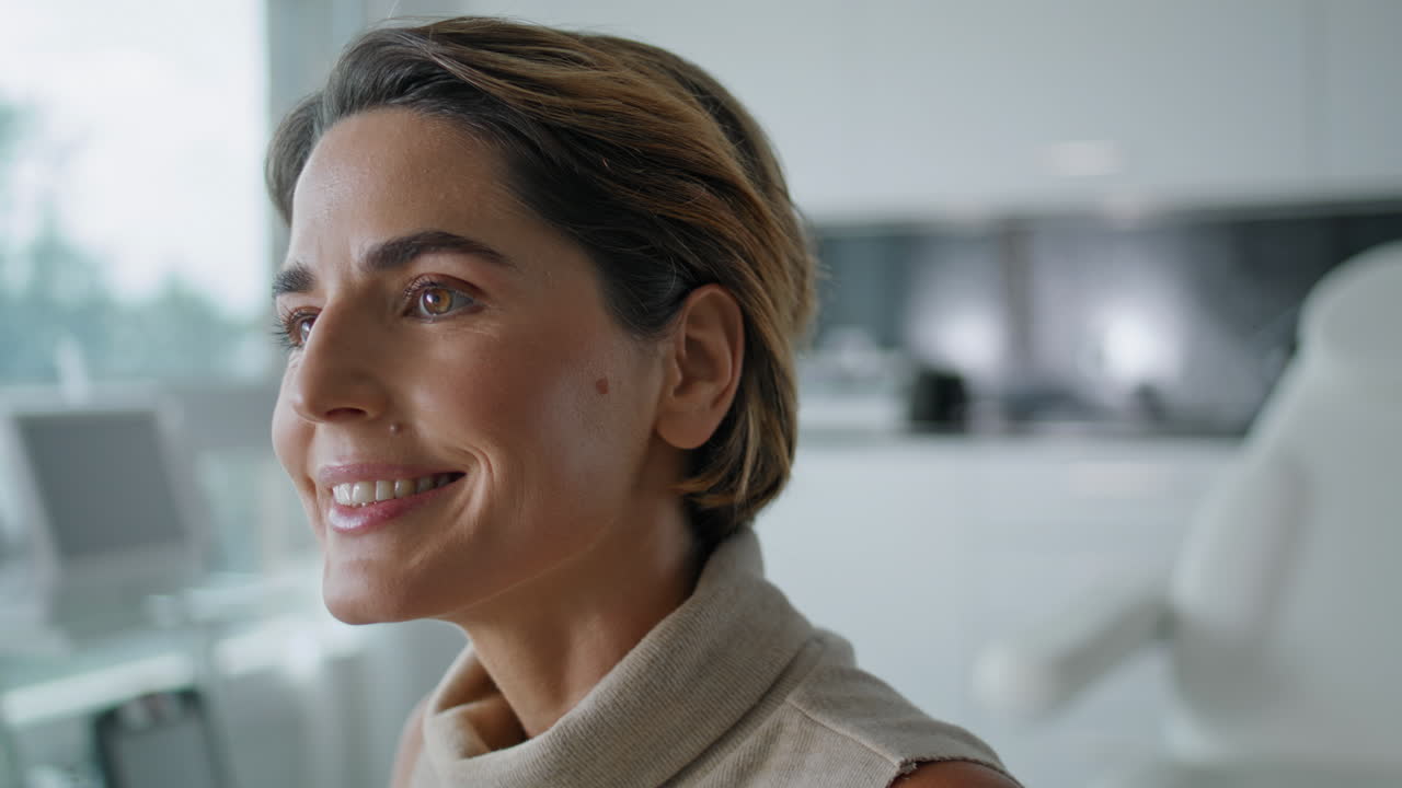 Portrait d'une femme d'âge moyen attrayante parlant, assise dans une clinique de cosmétologie.