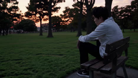 man sitting alone in a park at sunset