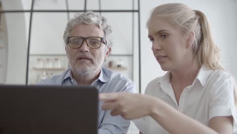 successful coworkers talking, using laptop and working together