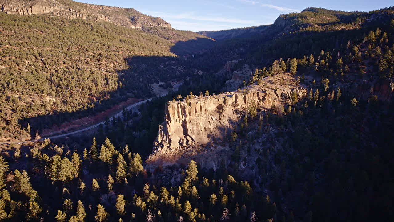 Ripresa aerea drammatica con drone del paesaggio di scogliere del New Mexico, con vegetazione rada e gruppi di alberi.