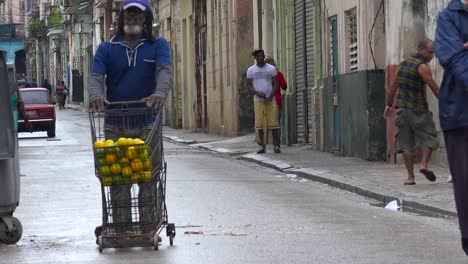 a street vendor wheels his goods down a street in the old city of havana cuba