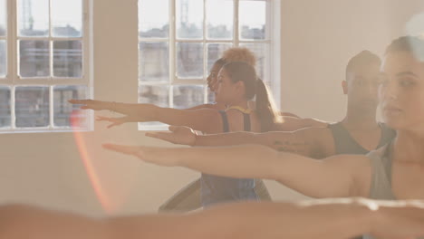 yoga class of young healthy people practicing warrior pose instructor woman teaching diverse group enjoying fitness lifestyle exercising in studio at sunrise