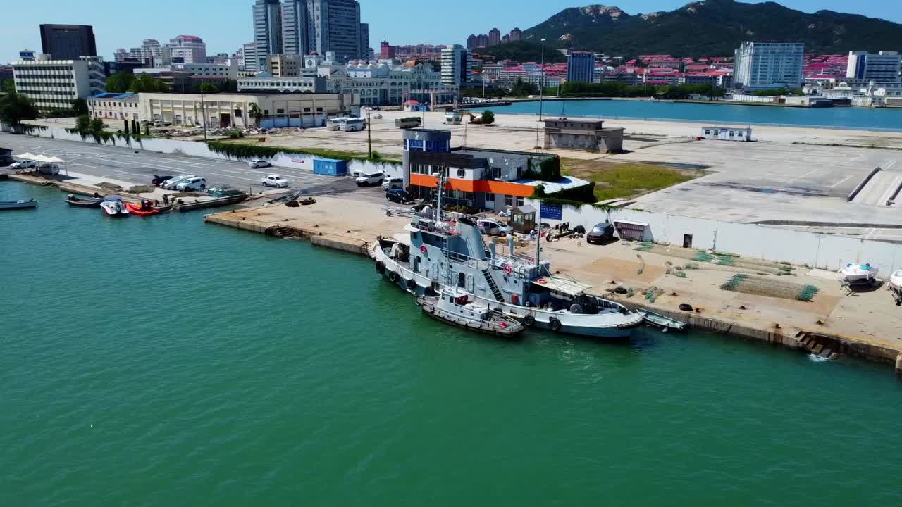 Aerial orbit view of pier with docked boats and beautiful skyline in Weihai - China
