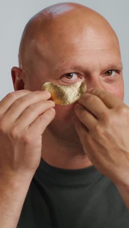 man applying gold eye patch