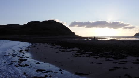 aerial - people walking at sunrise on island davaar, kintyre, scotland, tracking