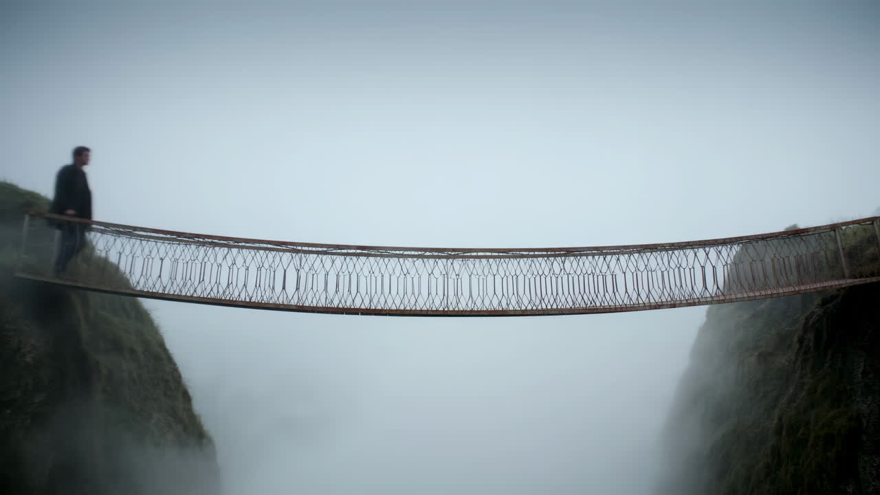 Man Walking on a Suspension Bridge Over a Misty Chasm