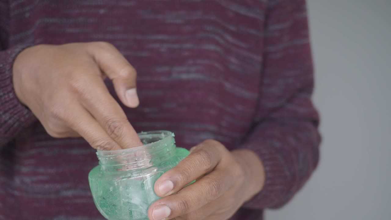Person Scooping Green Aloe Vera Gel from a Jar
