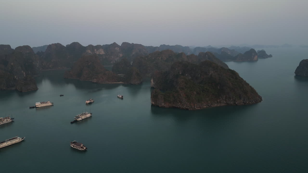 Aerial 4K drone footage over Ha Long Bay, Vietnam, showing tourist boats navigating among limestone karsts and emerald waters