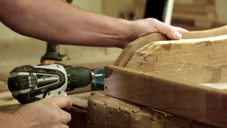 man drills in screw to wood frame - close up on hands