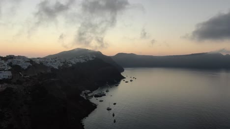 vista de avión no tripulado en grecia volando sobre santorini con la ciudad de oia casas blancas en un acantilado junto al mar mediterráneo al amanecer
