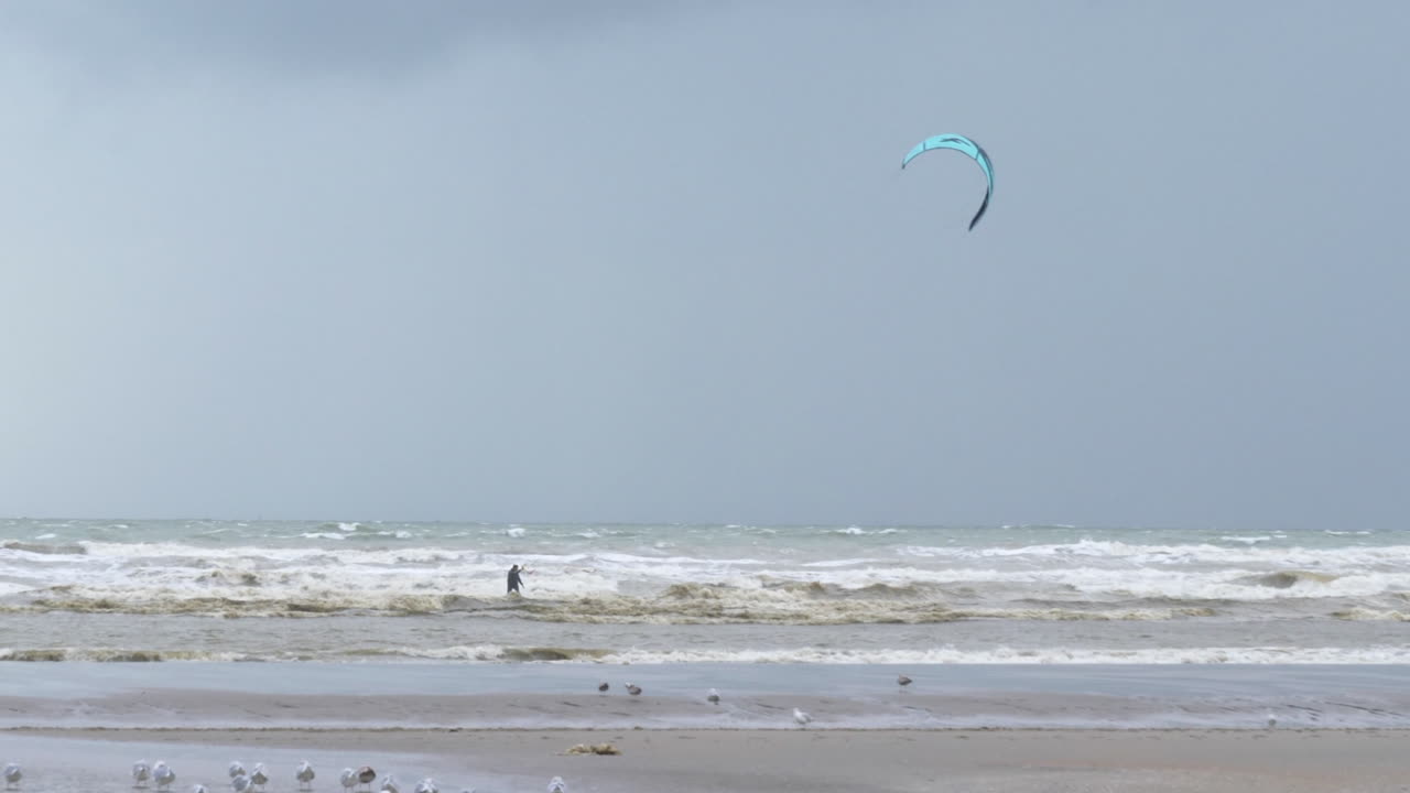 foto de seguimiento de una persona irreconocible haciendo kiteboard, playa de oostduinkerke, bélgica