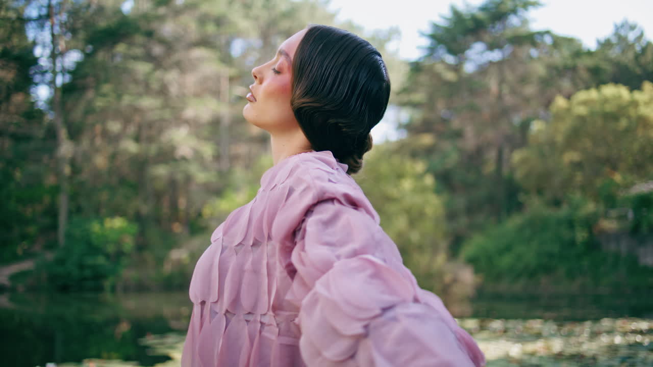 환상적인 모델이 푸른 숲의 연못에 서서 손을 움직이고 있다.