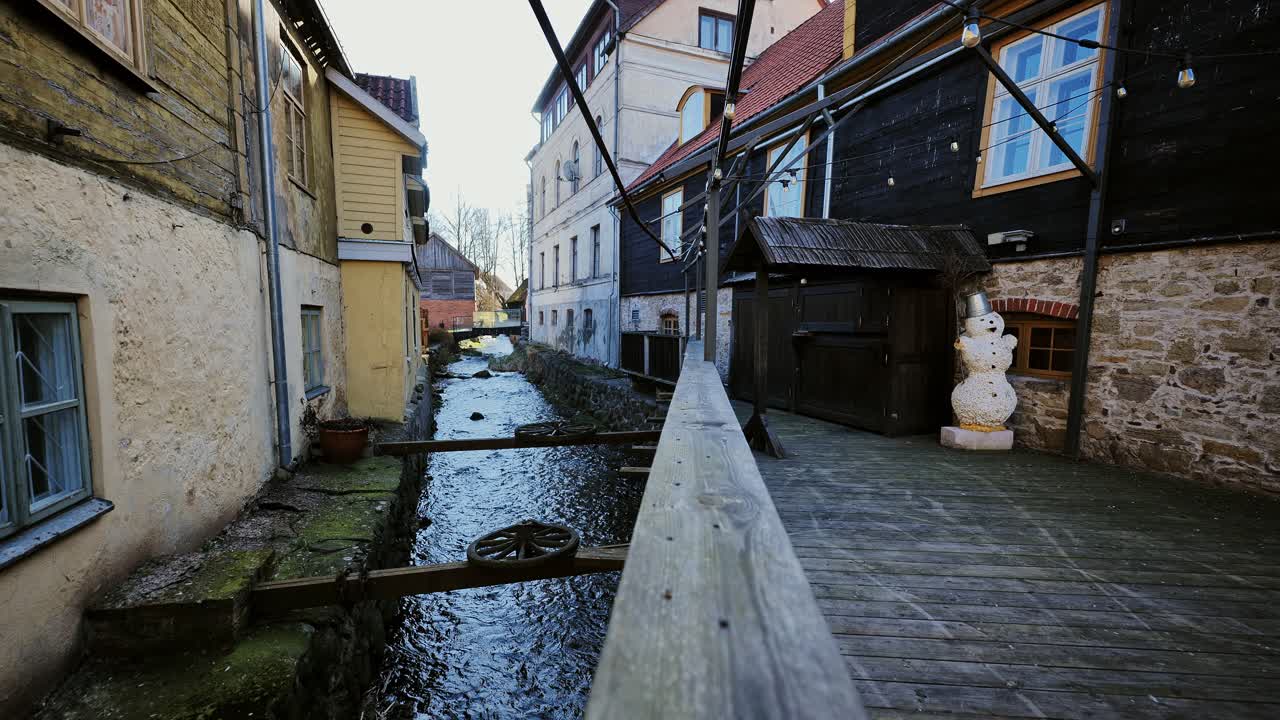 In Kuldīga, Latvia, Alekšupīte flows gently beside historic houses in spring sun