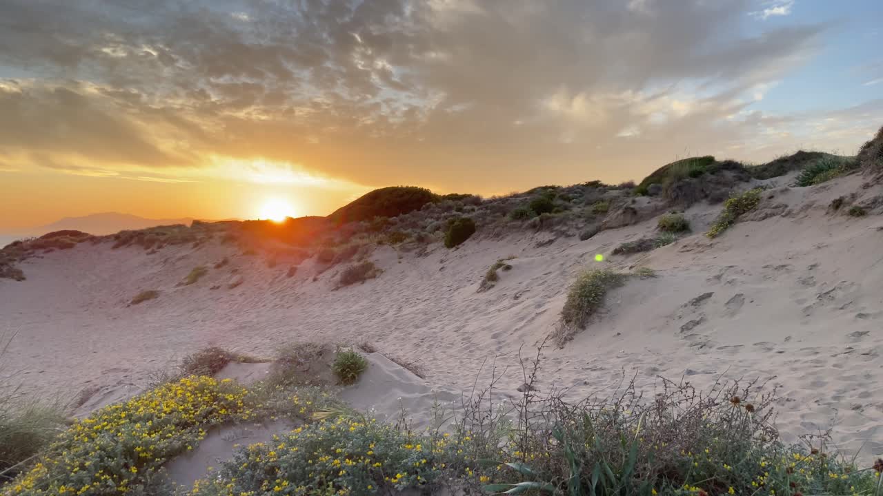 Crossing dunes on a beach under a magical and spectacular orange sunset.
