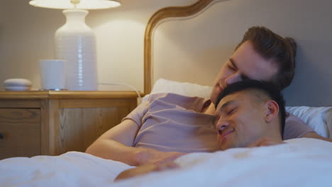 loving same sex male couple lying in bed at home asleep