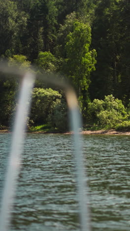 amazing virgin forest on bank of large tranquil lake view from boat stern. travelling by yacht to wild nature paradise on summer vacation. water journey