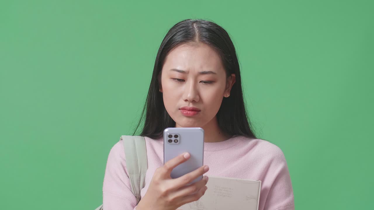 녹색 스크린 스튜디오에서 휴대전화를 사용하는 아시아 여성 학생