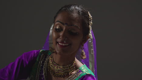 Close-Up-Of-Female-Kathak-Dancer-Performing-Dance-Wearing-Traditional-Indian-Dress-Seated-On-Floor-In-Spotlight-5