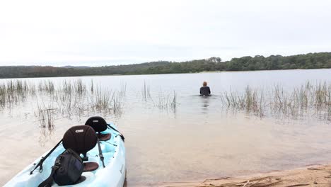 un hombre en traje de neopreno va a nadar en un lago entre juncos en australia