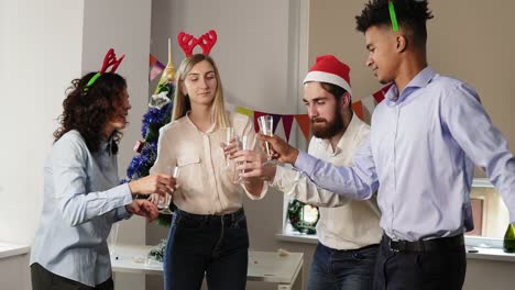 grupo multirracial de trabajadores de oficina felices bailando durante la fiesta corporativa de año nuevo con sombreros navideños y diadema de ciervo