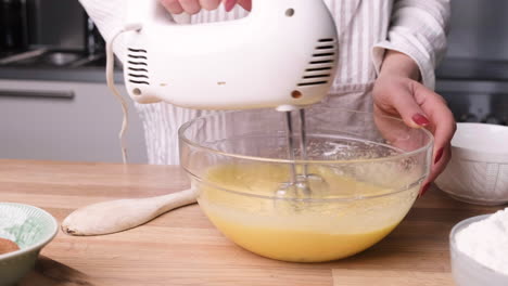 baker using handheld electric mixer on cake batter