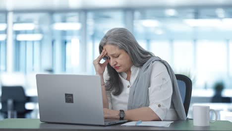 tensed indian senior female manager working on laptop