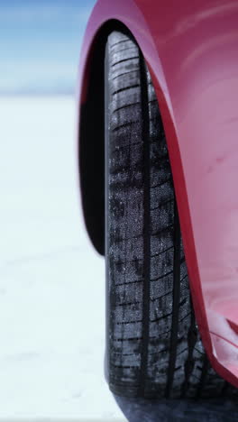 close-up of a winter tire on a red car in the snow