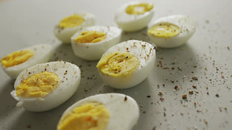 video de primer plano de las mitades de pimienta de huevos duros cocidos en fondo gris