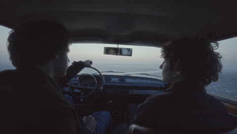 couple sitting inside car, looking out over frozen lake at dusk