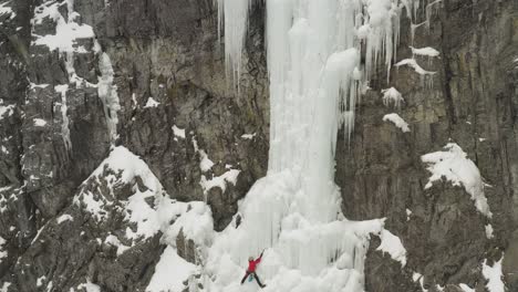 Breathtaking-aerial-view-of-ice-climber-scaling-frozen-cascade-Mount-Kineo-4K