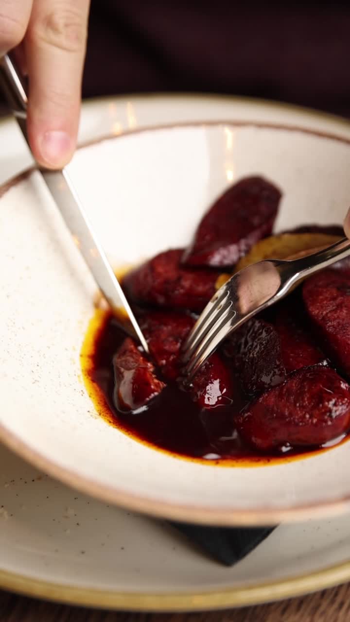 Person cutting a delicious dish with knife and fork
