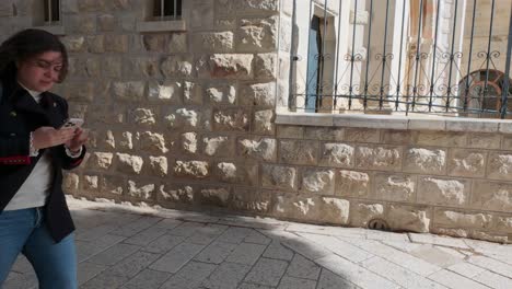 young tourist walking and using smartphone in jerusalem old city. slow motion.
