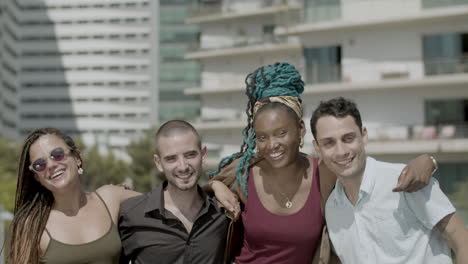 front view of smiling coworkers hugging and looking at camera