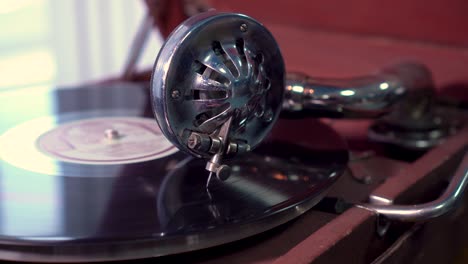 head of a gramophone with a metal needle slides on a vinyl record. close-up, selective focus. old vintage phonograph.