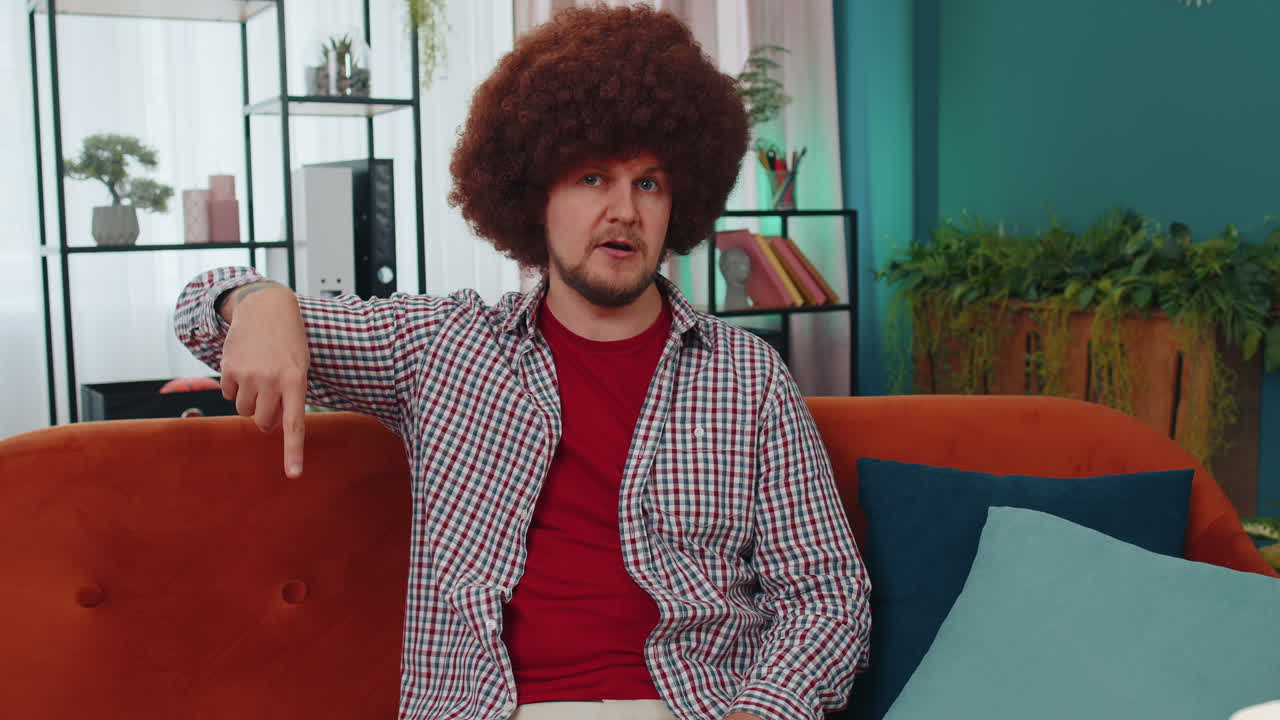 joven mirando la publicidad de la cámara haciendo un gesto telefónico como dice hola me llamas en casa