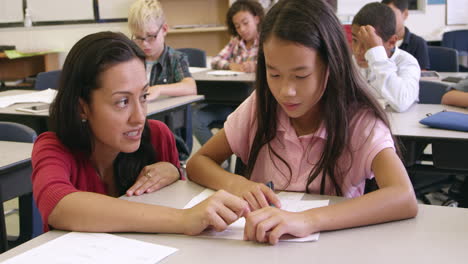 Profesora-Ayudando-A-Una-Colegiala-Asiática-En-Su-Escritorio,-Filmada-En-R3d