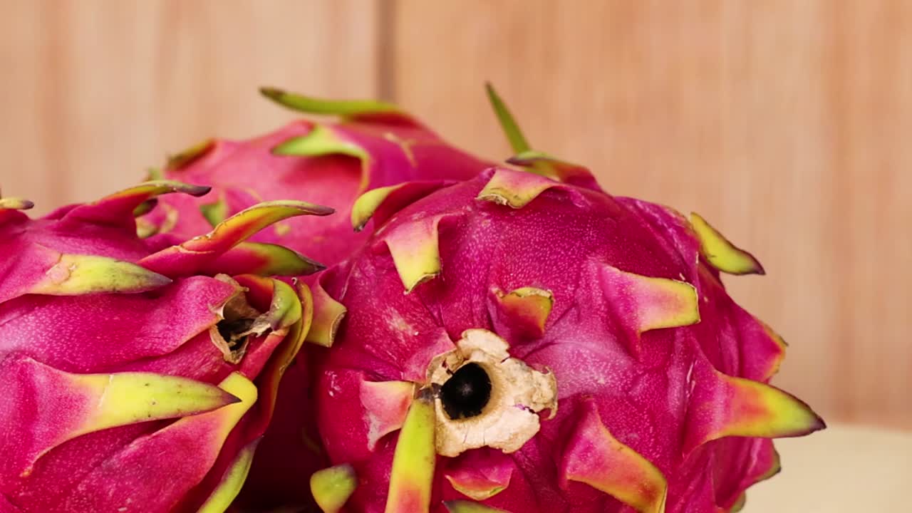 A detailed view of fresh dragon fruits showcasing their vibrant pink skin and green scales.