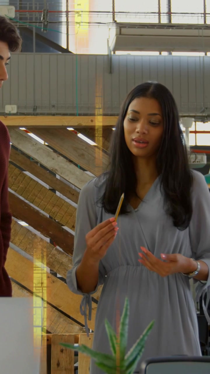 Vertical video: Woman lifting yellow pencil and explaining design concept in studio with laptop