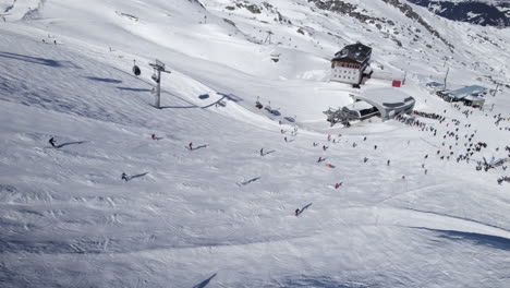 aerial birds eye shot showing group of skier skiing down white snow-capped slope of mountain