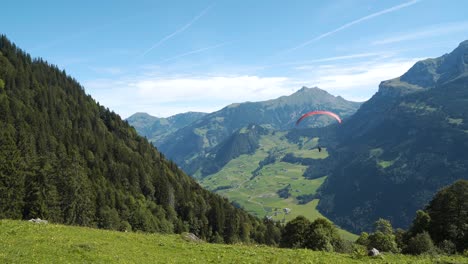 paraglider flying down the mountain in the swiss alps, wide shot, handheld