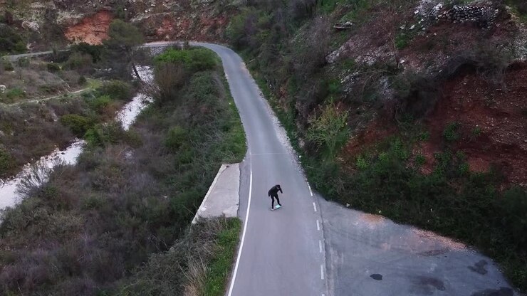 Aerial view of young man doing surfskate on a mountain road
